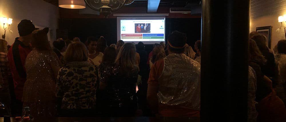 Teams answer quiz questions together in a pub setting